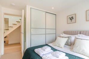 A bedroom with a bed, pillows, a green blanket, and a set of towels. - 3 Bed in Padstow (oc-p36068) (Constantine Bay)
