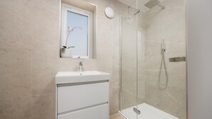 A modern bathroom with a glass-enclosed shower, a white sink, and a window with a plant. - 4 Bed in Padstow (oc-p36069) (Constantine Bay)