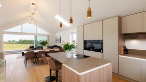 A modern kitchen with a central island, pendant lighting, and a view of the outdoors. - 4 Bed in Padstow (oc-p36070) (Constantine Bay)