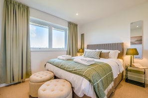 Ein Hotelzimmer mit einem Bett, zwei Nachttischlampen, einem Fenster und Blick zum Himmel.