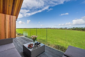 Ein Balkon mit Glasgeländer, der auf eine Wiese blickt.