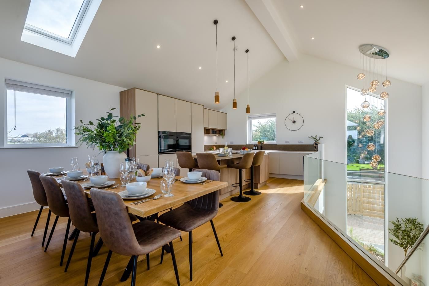 A modern dining area with a wooden table set for six, surrounded by cushioned chairs.