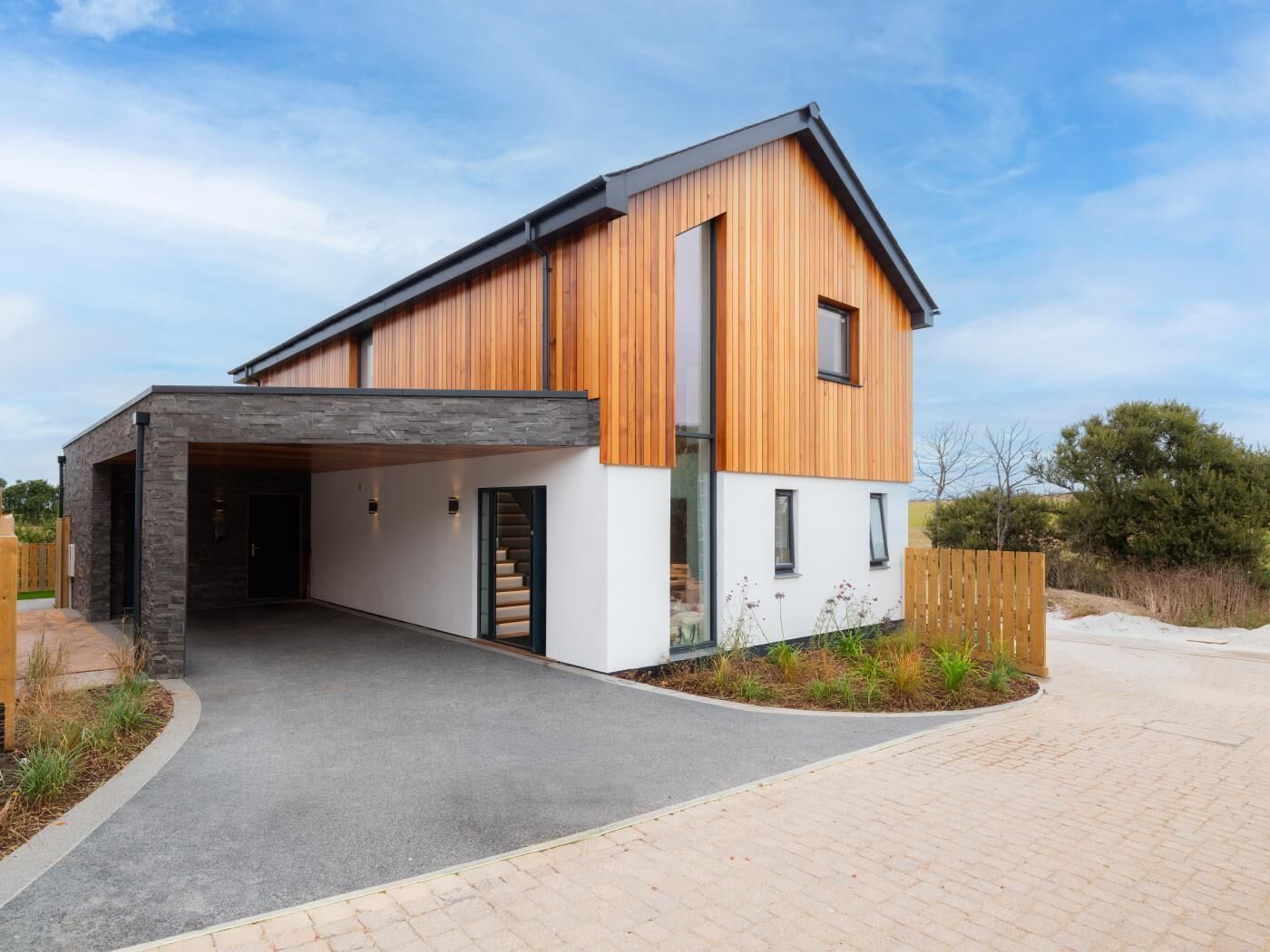 A modern two-story house with a covered driveway and a wooden exterior.