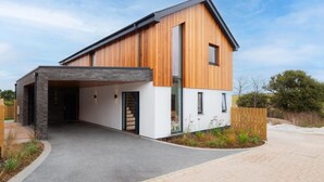 A modern two-story house with a covered driveway and a wooden exterior. - 4 Bed in Padstow (oc-p36070) (Constantine Bay)