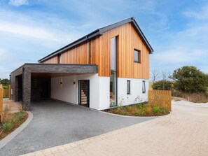 Ein modernes, zweistöckiges Haus mit überdachter Auffahrt und Holzfassade.