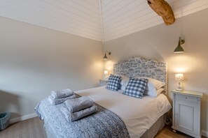 A bedroom with a bed, two bedside tables, a headboard with a pattern, and a hanging light fixture. - 1 Bed in Peasmarsh (oc-staohf) (Peasmarsh)
