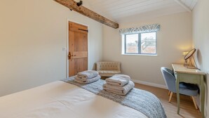 Une chambre à coucher avec un grand lit, une porte en bois, une fenêtre, une chaise et un bureau avec une lampe.