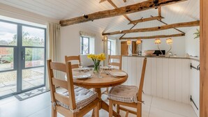 Un coin repas avec une table ronde, des chaises en bois et un vase rempli de fleurs jaunes.