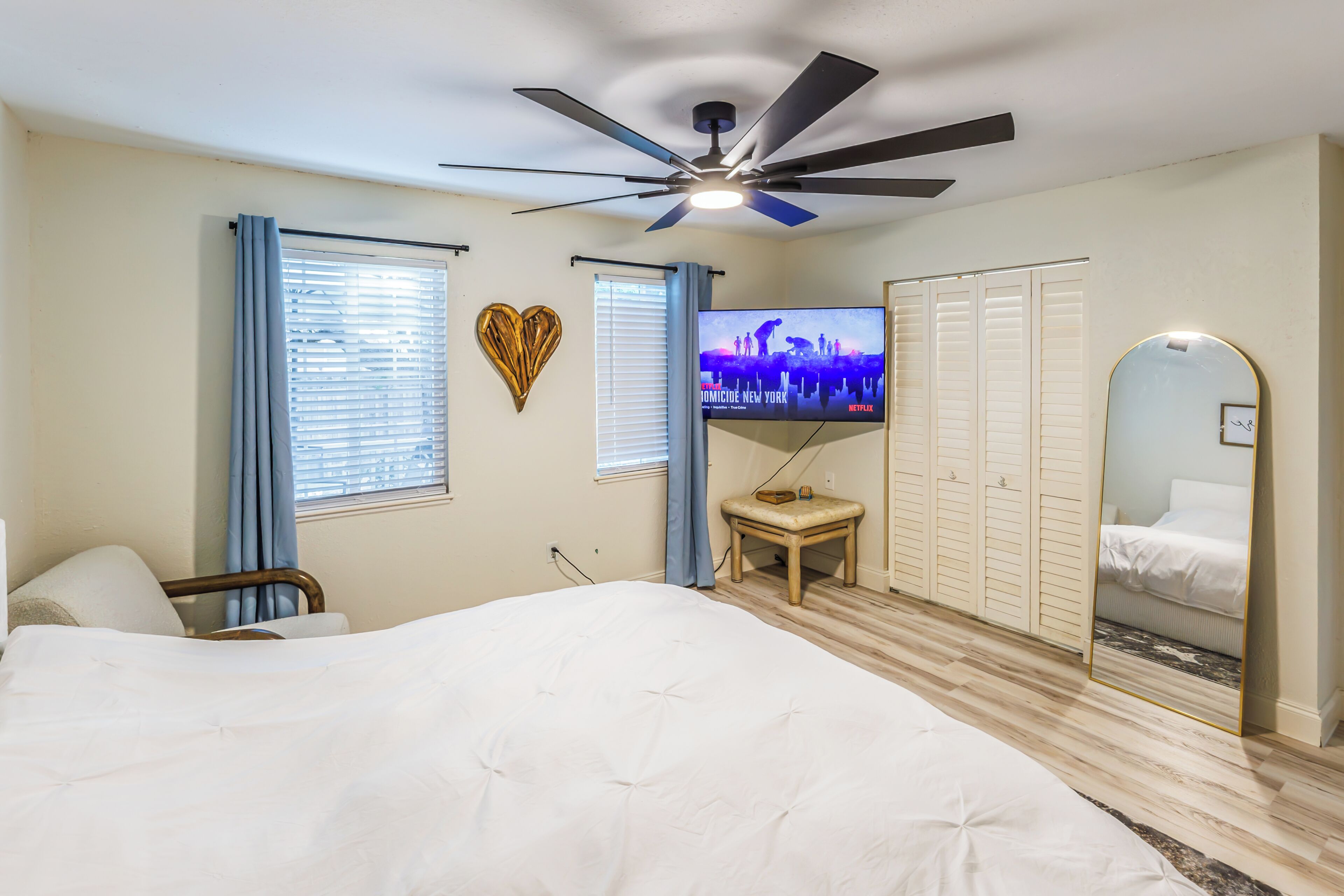 Una camera da letto con un letto, una ventola a soffitto, una TV, un armadio e uno specchio.