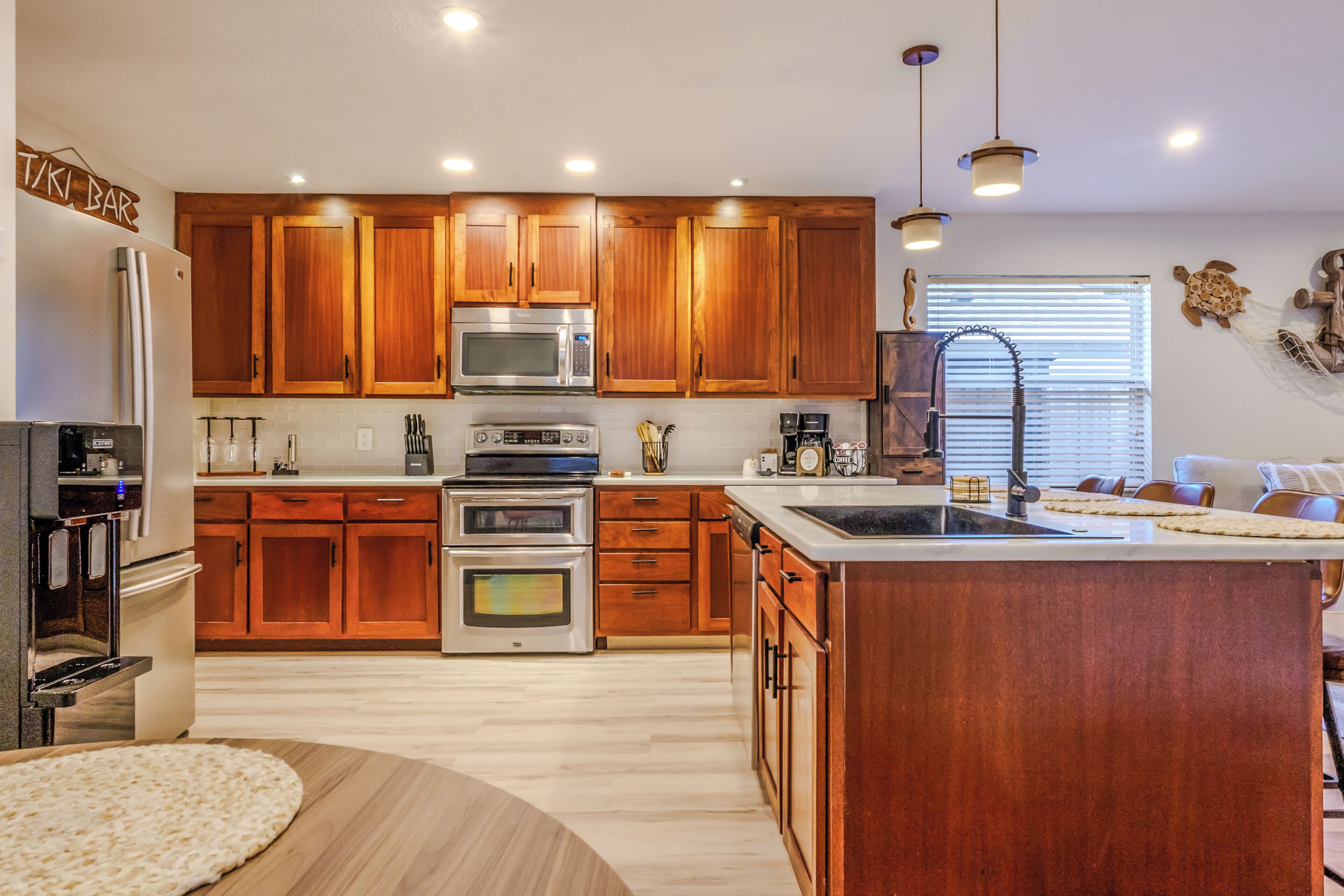 Una cocina con armarios de madera, electrodomésticos de acero inoxidable, una isla grande y vista al área de estar.