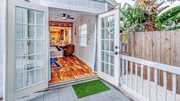 Una casa con terraza de madera, puerta corrediza de vidrio, ventilador de techo y una alfombra pequeña.