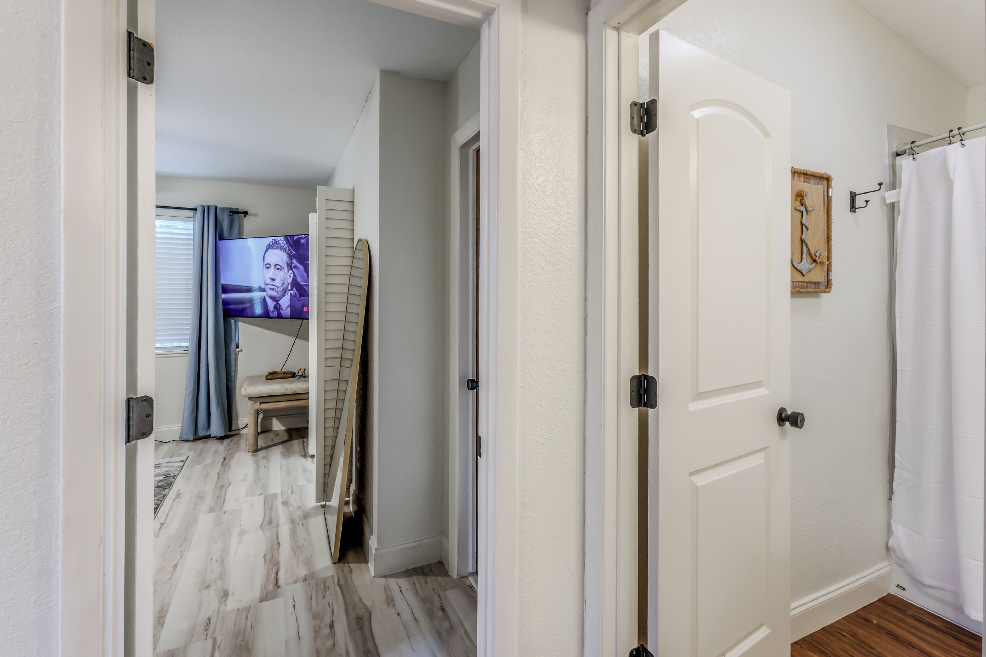 Un couloir avec un téléviseur, une porte et un rideau de douche.