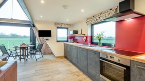 A modern kitchen with a large window, a dining area with a table and chairs, and a view of the outdoors.