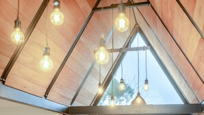 A triangular ceiling with exposed wooden beams and hanging light bulbs.
