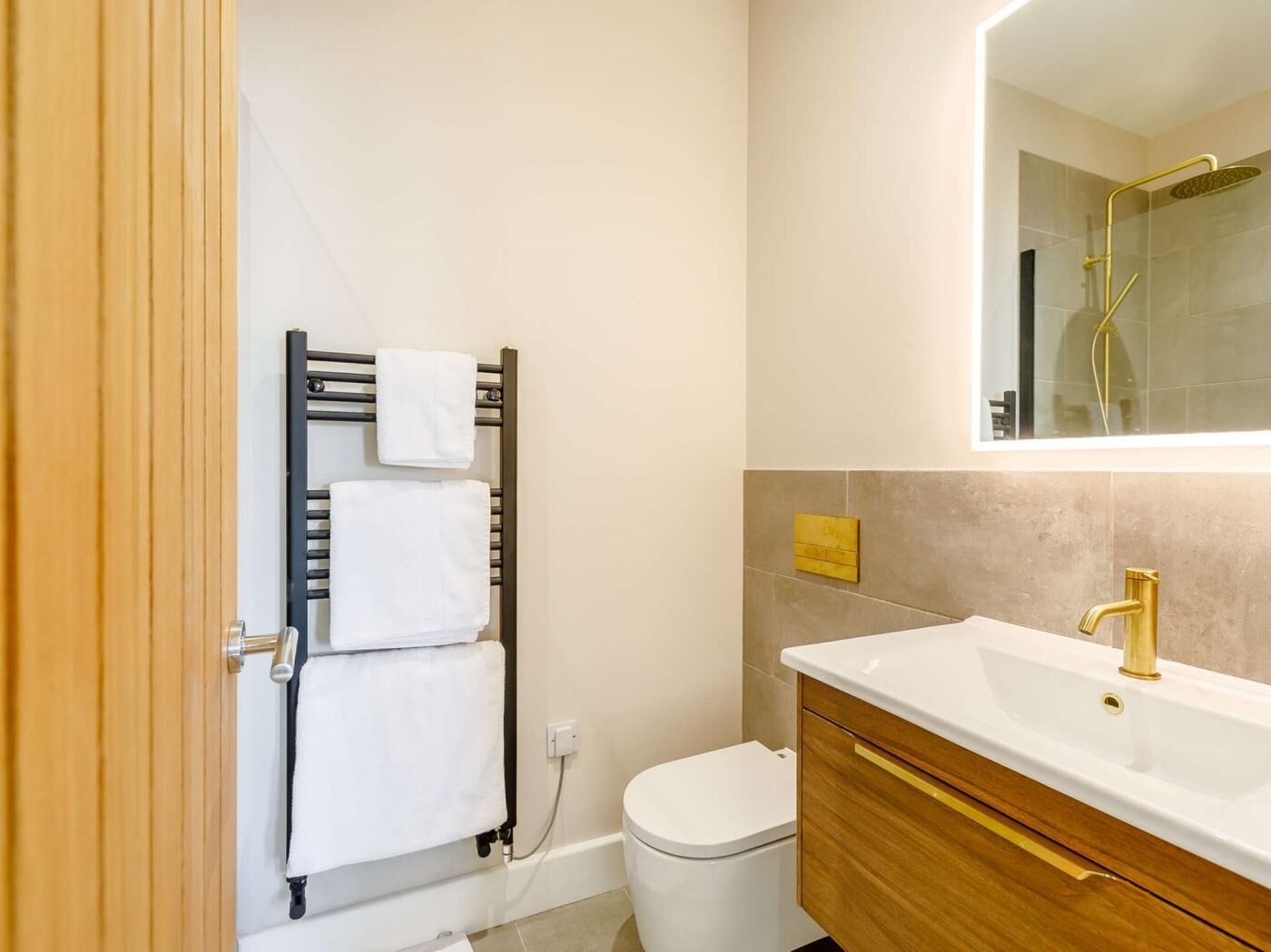 Uma casa de banho moderna com sanita, lavatório e suporte para toalhas.