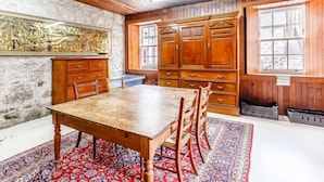 Un coin repas avec une table et des chaises en bois, un grand meuble et un tapis à motifs.