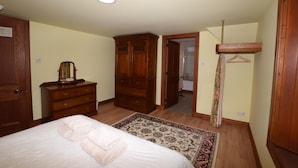 Une chambre à coucher comprenant un lit, une commode, une armoire et une salle de bain visible à travers une porte ouverte.