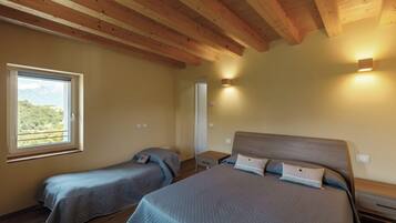 A bedroom with two beds, wooden beams on the ceiling, a window with a view, and bedside lamps.