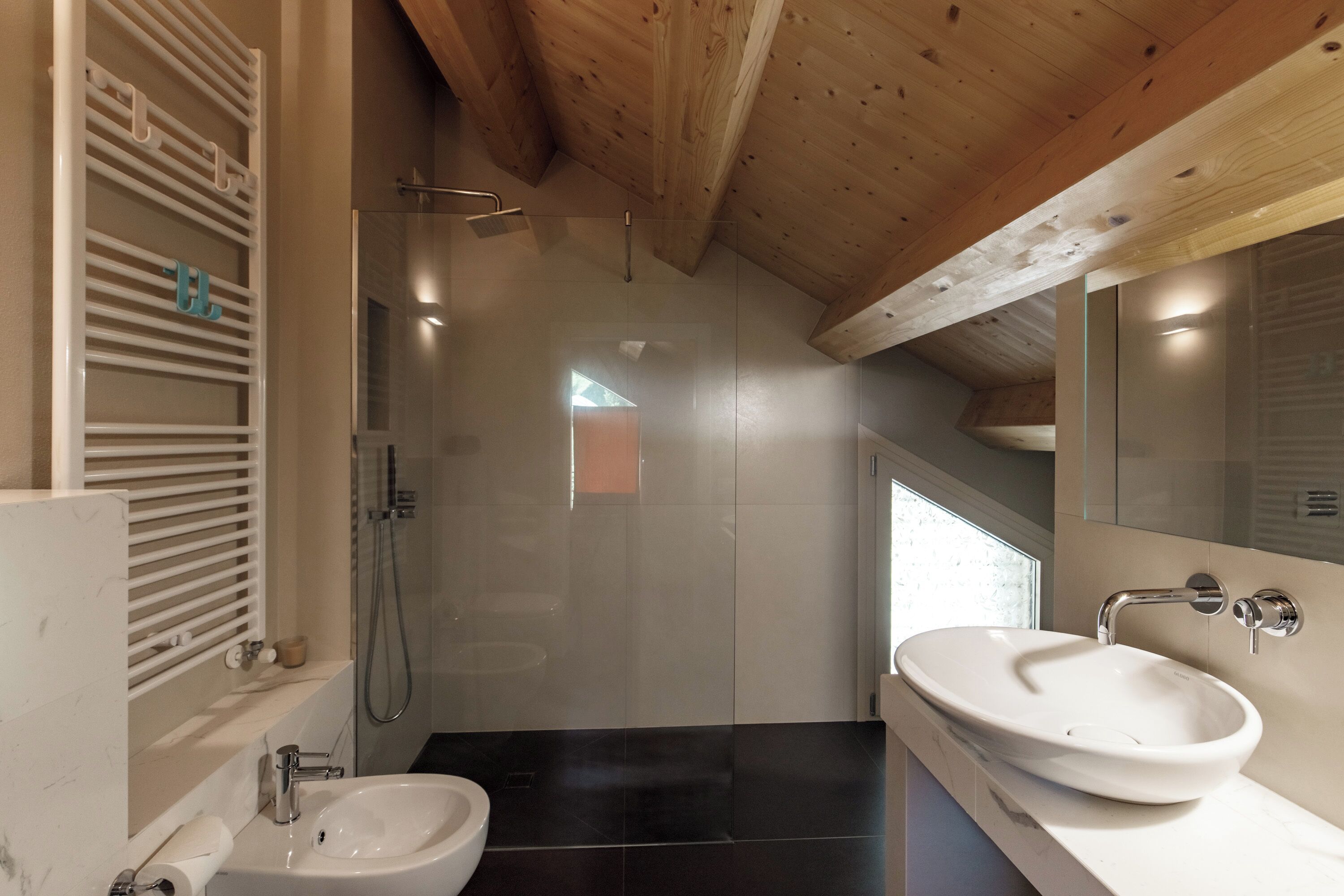 A modern bathroom with a glass-enclosed shower, a white sink, and a wooden ceiling.