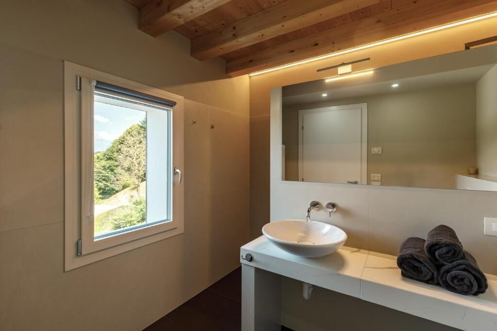 Un baño con ventana, lavamanos y toallas.