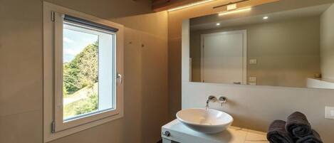 A bathroom with a window, a sink, and towels.