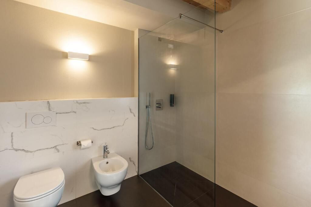 Un baño moderno con inodoro, bidé y ducha con mampara de vidrio.