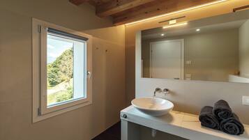 Un baño con ventana, lavamanos y toallas.
