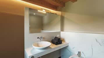 A modern bathroom with a white sink, a mirror, and a small pedestal sink.