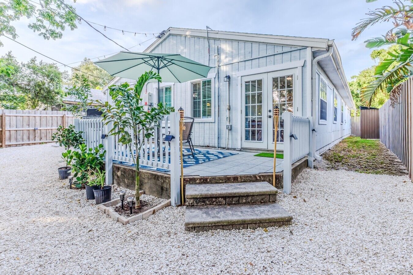 A house with a covered patio, a fenced deck, and potted plants.