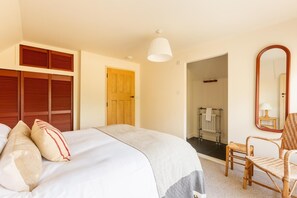A hotel room with a bed, a chair, a mirror, and a door leading to a bathroom. - 4 Bed in Hartland (oc-s37525) (Hartland)
