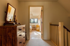 A hallway leading to a bedroom with a wooden dresser, a mirror, and a bed with a window. - 4 Bed in Hartland (oc-s37525) (Hartland)