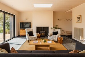 A modern living room with a fireplace, two armchairs, a sofa, a coffee table, and a television. - 4 Bed in Hartland (oc-s37525) (Hartland)