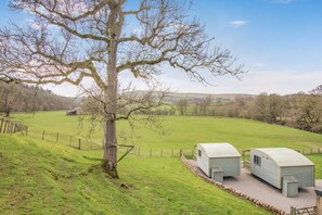A rural landscape with a large tree, a fenced field, and two small wooden structures. - 1 Bed in Smardale (oc-e37511) (Smardale)