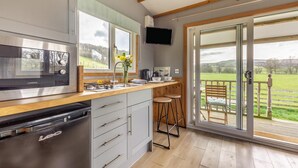 A modern kitchen with a built-in dishwasher, a large window, and a dining area with a view of the countryside.
