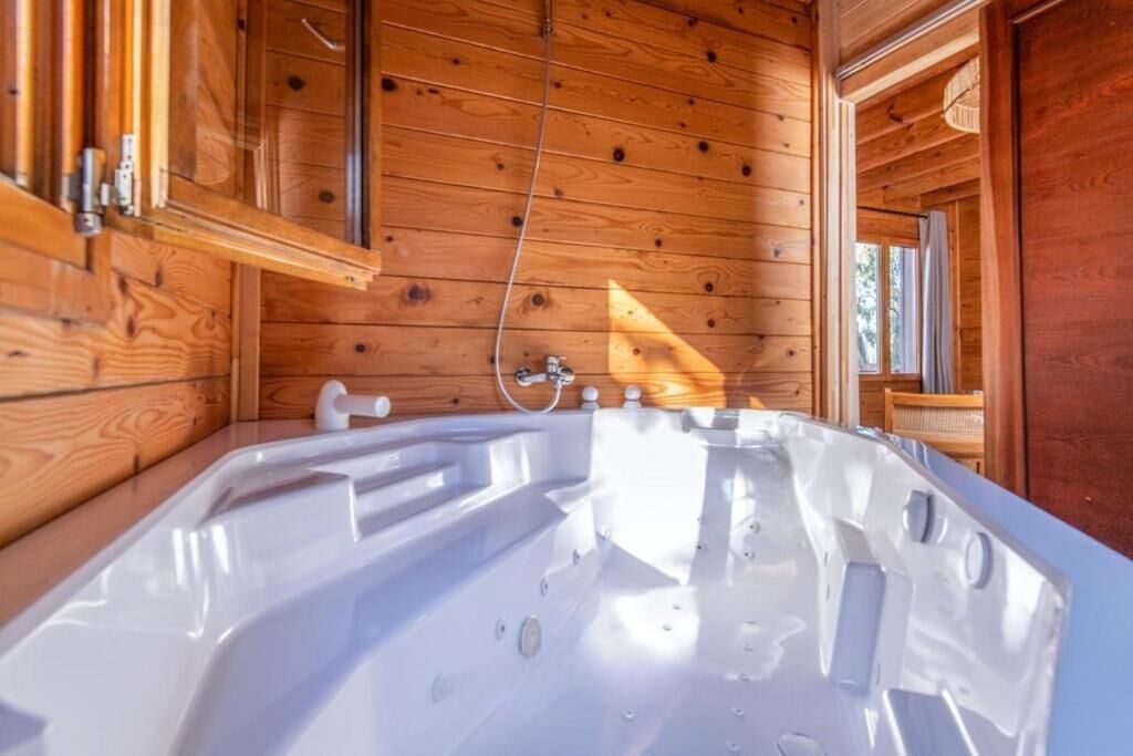 Interior de una cabaña de madera con jacuzzi, paredes de madera y una ventana.