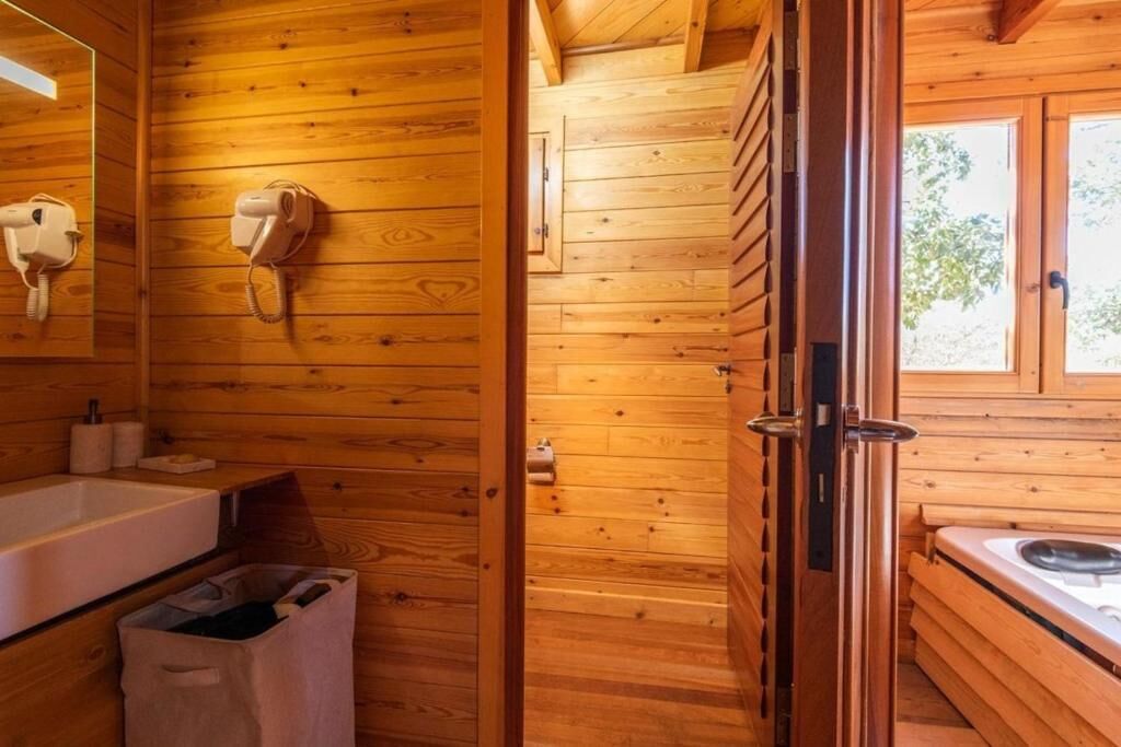 A wooden cabin interior with a wooden wall, a white sink, a towel rack, and a window.