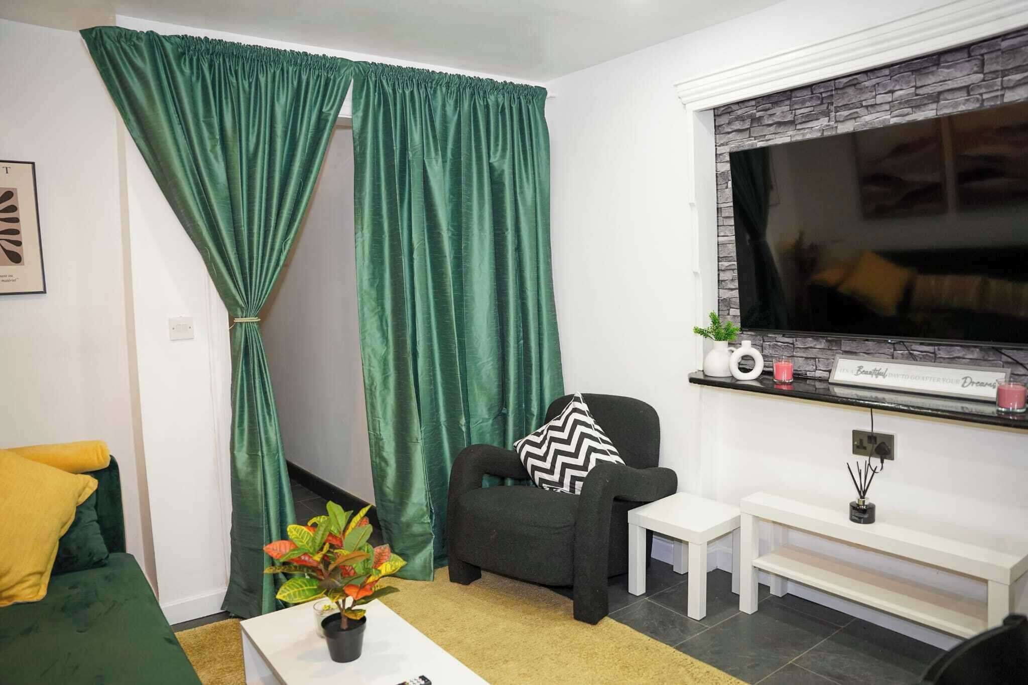 Ein Wohnzimmer mit einer Couch, einem Sessel, einem Couchtisch, einem Fernseher und einer Pflanze.