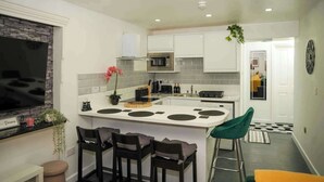 A compact kitchen with a central island, built-in microwave, and white cabinetry.
