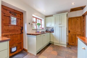 A kitchen with wooden cabinetry, a window with a view, and a built-in oven. - 3 Bed in Longnor (oc-r34925) (Longnor)