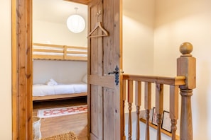 A wooden room with bunk beds, a hanging coat rack, and a wooden staircase. - 3 Bed in Longnor (oc-r34925) (Longnor)