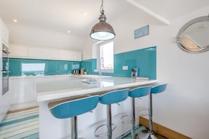 A modern kitchen with a central island, bar stools, and a pendant light. - 3 Bed in Selsey (oc-s36028) (Selsey)