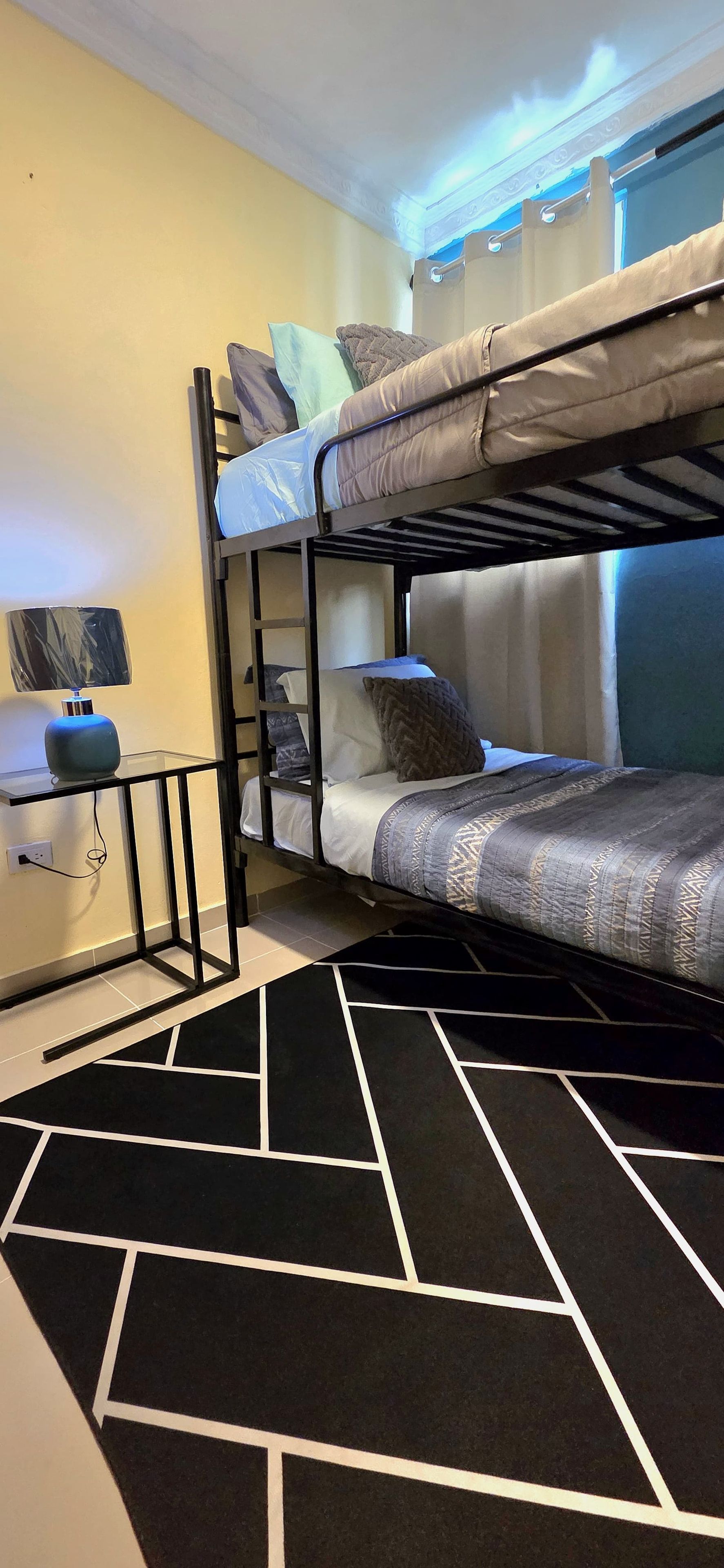 A bunk bed room with a desk and a lamp.