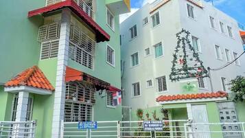 A multi-story building with a green facade, a red roof, and a white gate.