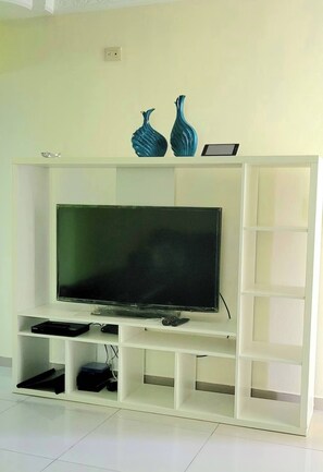 A white entertainment unit with a flat-screen TV, two decorative vases, and a tablet. - Spacious and Comfortable 3-bedroom 2 Bathroom in Santo Domingo Este (Santo Domingo Este)