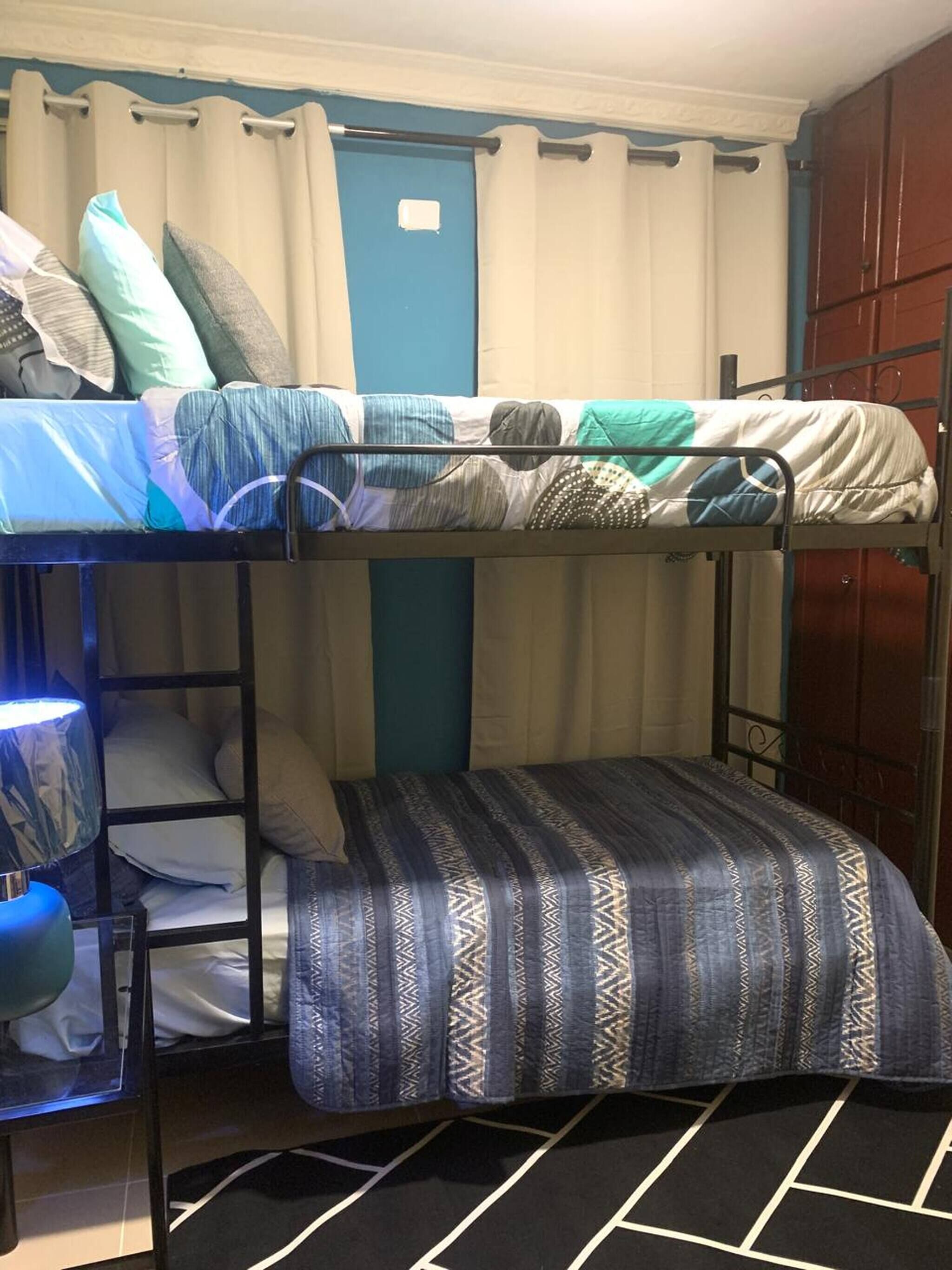 A bunk bed with patterned bedding, a lamp, and a door in the background.