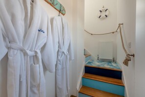 A staircase with a blue and wooden finish, white walls, and a life preserver hanging on the wall. - 1 Bed in Selsey (oc-s36029) (Selsey)
