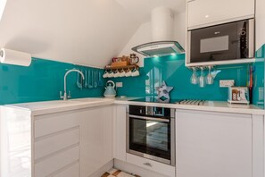 A modern kitchen with white cabinets, a built-in oven, and a microwave. - 1 Bed in Selsey (oc-s36029) (Selsey)
