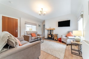A modern living room with a fireplace, sofas, a coffee table, and a TV mounted on the wall.