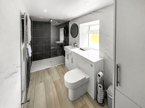 A modern bathroom with a shower, toilet, sink, and mirror.