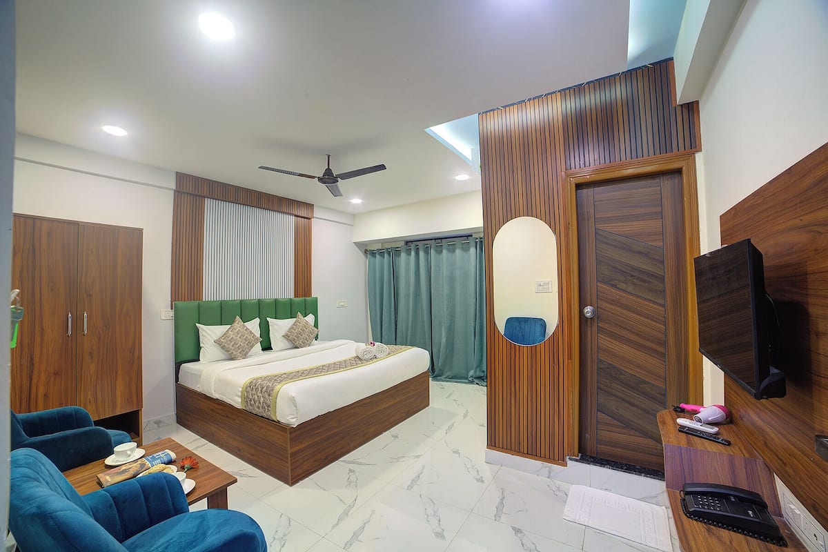 Una habitación de hotel con cama, escritorio, silla, televisor, ventilador de techo y armario.